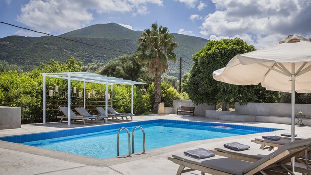 A swimming pool with lounge chairs and a pergola, surrounded by greenery and mountains. - Emily Villas (Kefalonia)