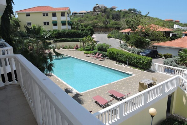 A pool area with lounge chairs and a view of surrounding buildings. - Condo at Blue Bay Golf and Beach Resort (Sint Michiel)
