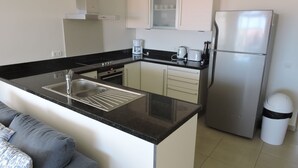 Eine kompakte Küche mit Spüle, Edelstahl-Kühlschrank und Kaffeemaschine.