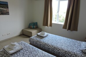 A room with two beds, a small seating area, and a window with curtains. - Condo at Blue Bay Golf and Beach Resort (Sint Michiel)