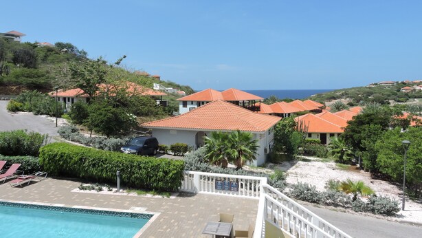 Ein Resort mit mehreren Gebäuden, einem Schwimmbad und Blick aufs Meer.