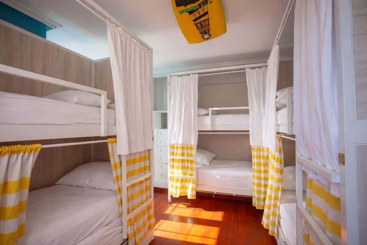 A room with bunk beds, white curtains, and a yellow hanging object.