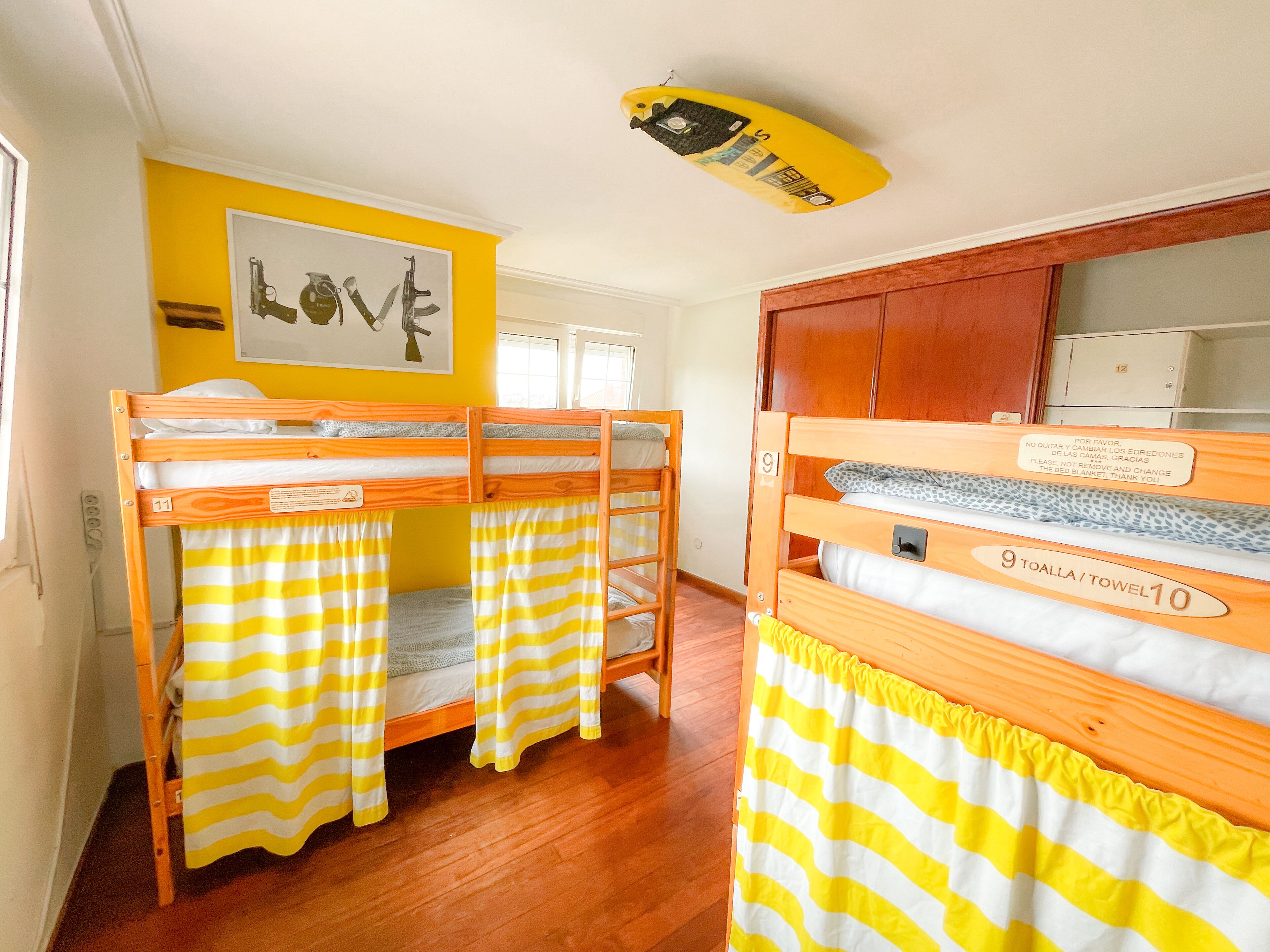 Een kamer met stapelbedden, houten kasten en een bed met kussen en deken.