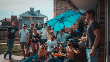 A group of people gathered outdoors, some sitting and others standing, with a brick building in the background.