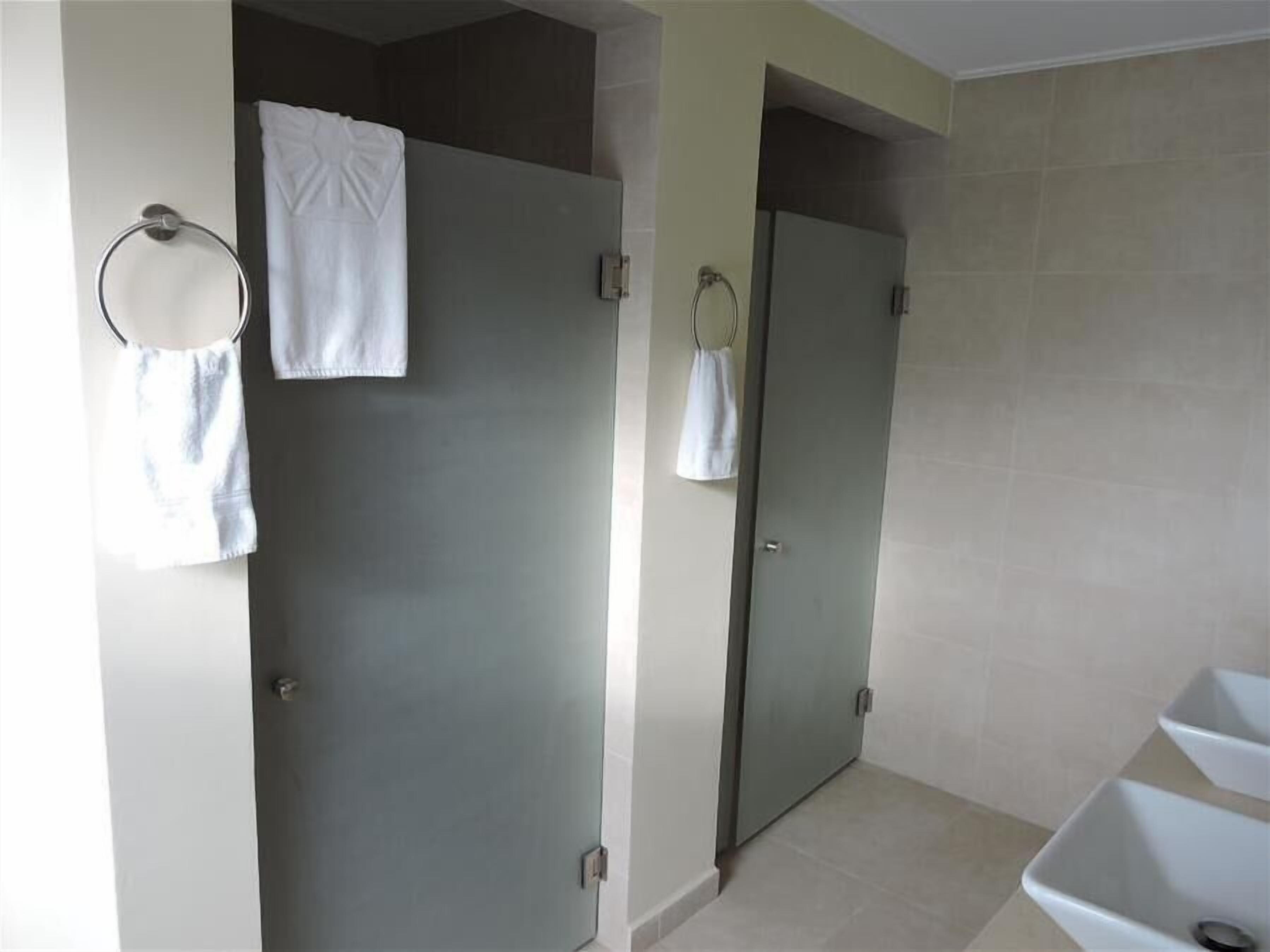 Une salle de bain avec deux portes, un porte-serviettes et un lavabo.