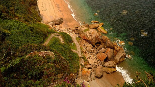 A coastal landscape with a sandy beach, cliffs, and a clear view of the sea. - Hotel La Colina (Gijon)