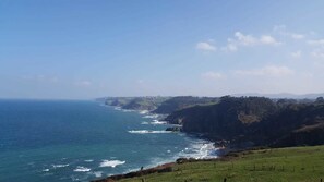 Paisaje costero con vista despejada al océano y colinas lejanas.