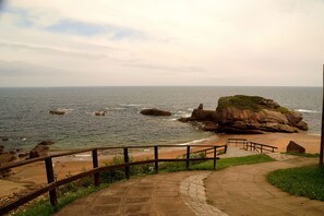 Un paseo marítimo costero con baranda de madera, que conduce a un promontorio rocoso junto al mar.