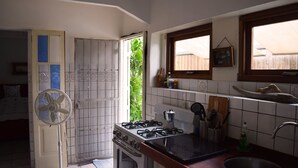 A compact kitchen with a gas stove, an oven, a sink, and a fan. - Ocean-side Home (Willemstad)