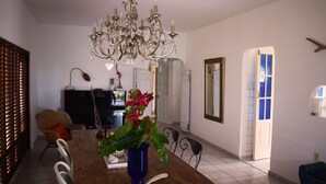 A dining area with a wooden table, chairs, a chandelier, a piano, and a mirror. - Ocean-side Home (Willemstad)