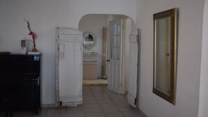 A hallway with a white door, a mirror, and a black piano. - Ocean-side Home (Willemstad)