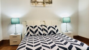 Une chambre à coucher avec un lit, deux tables de chevet et un tableau accroché au mur.