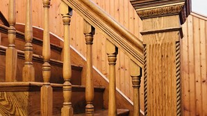 Un escalier en bois, doté d’une balustrade et d’un pilier décoratif.