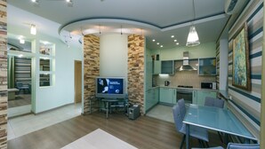 A modern kitchen with a built-in microwave, stove, and cabinets. There is a dining area with a glass table and chairs.