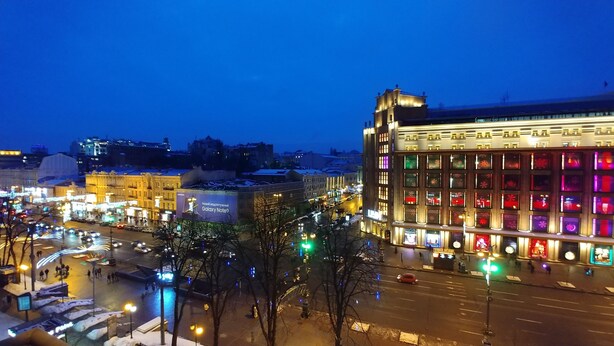 A cityscape at night with illuminated buildings and a busy street.