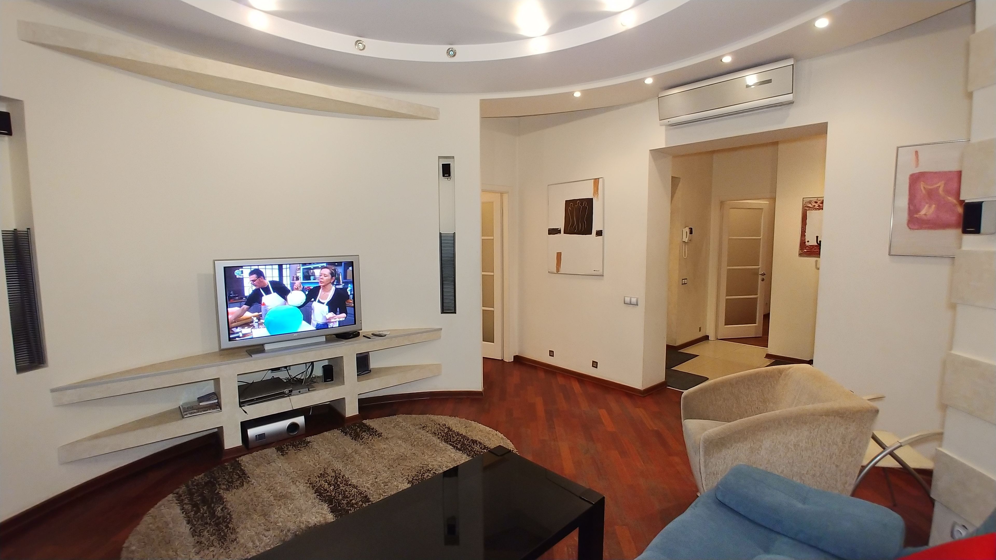 En moderne stue med et fladskærms-tv, et sofabord og to sofaer.