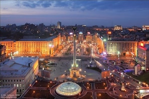 A city square with a prominent monument, surrounding buildings, and a dome structure.