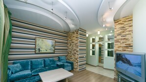 A modern living room with a sofa, a coffee table, a flat-screen TV, and a stone accent wall.