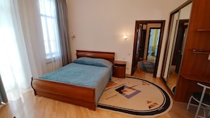 A bedroom with a wooden bed, a nightstand, a mirror, and a patterned rug.