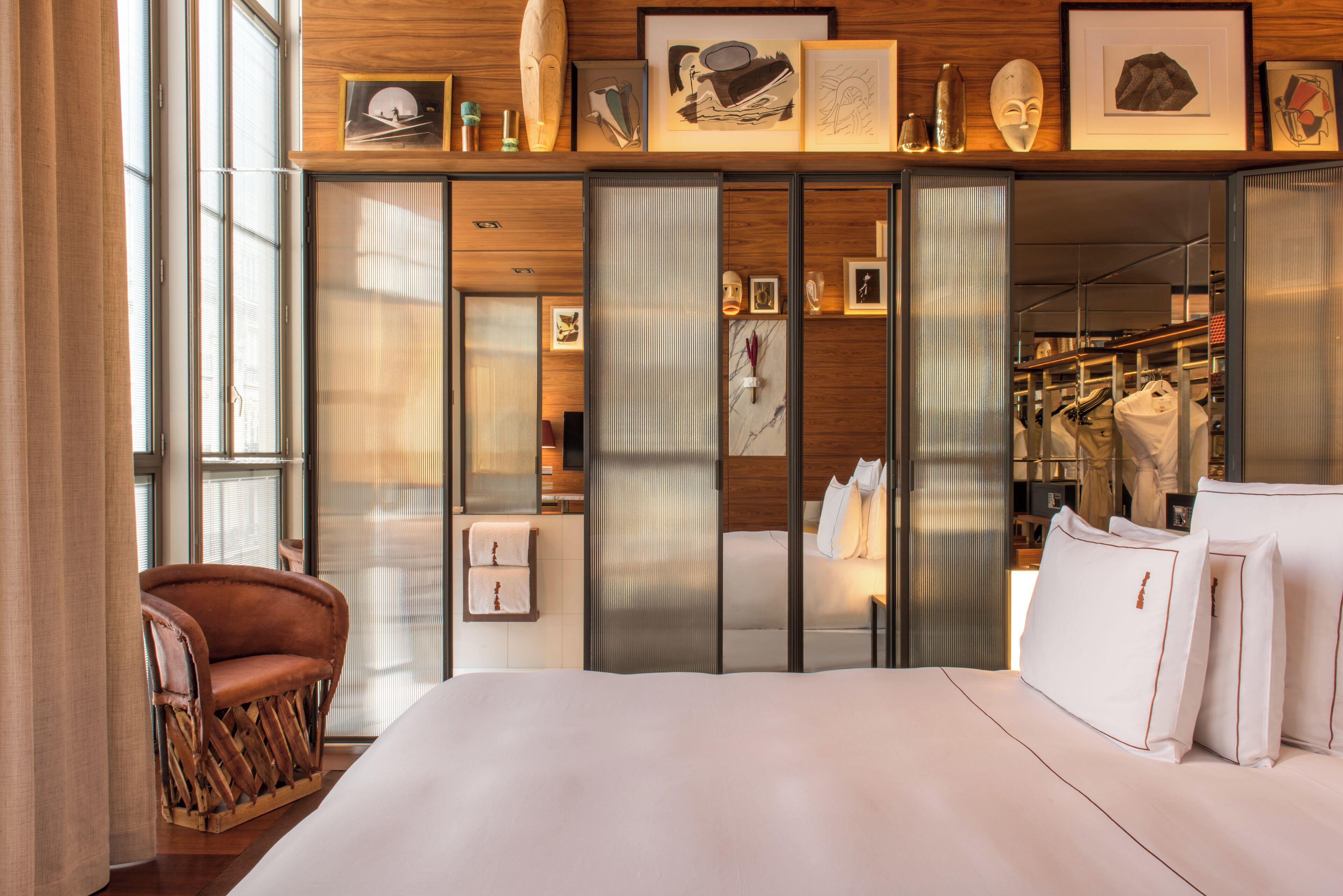 Una habitación de hotel moderna con una cama grande, una zona de estar y un armario con puertas correderas.