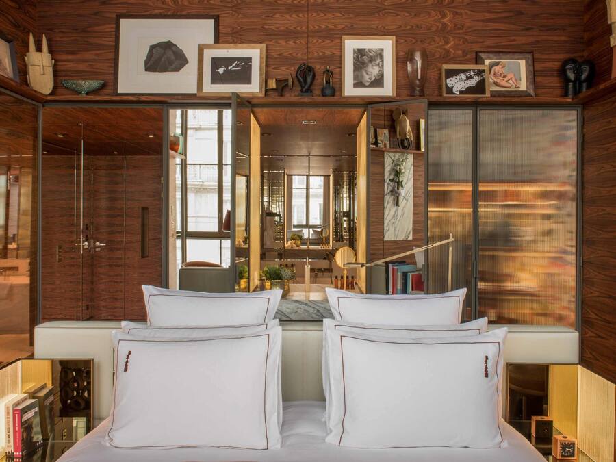 A bedroom with a large bed, a walk-in closet, and a mirrored wardrobe.