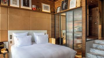 Een moderne hotelkamer met een groot bed, een houten hoofdbord en een glazen deur naar een balkon.