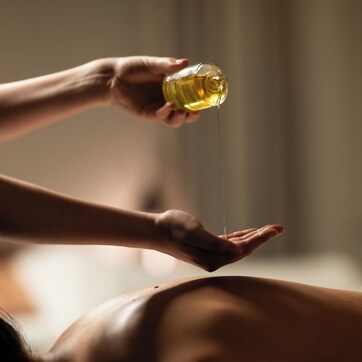 A person applying oil to another person's back.