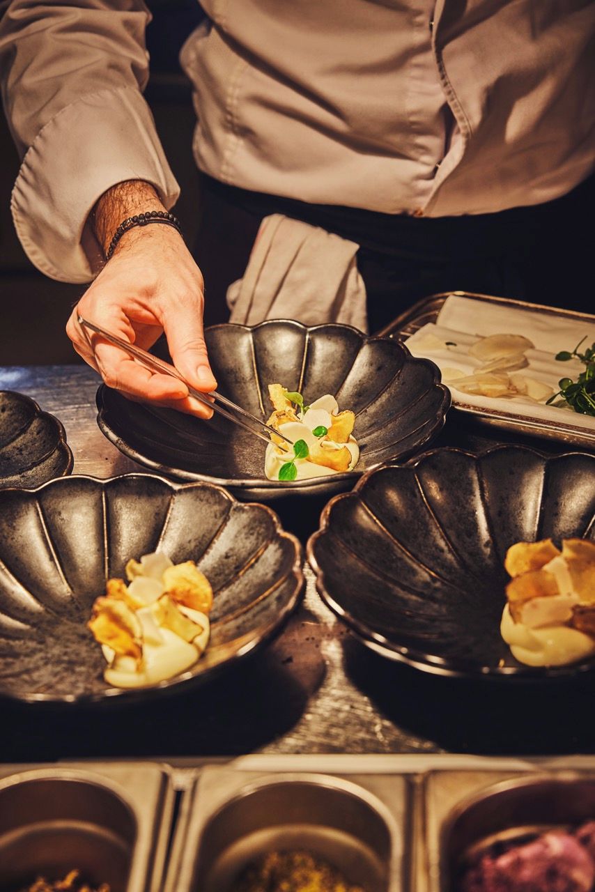 Iemand serveert eten uit een zwarte, golfvormige kom.