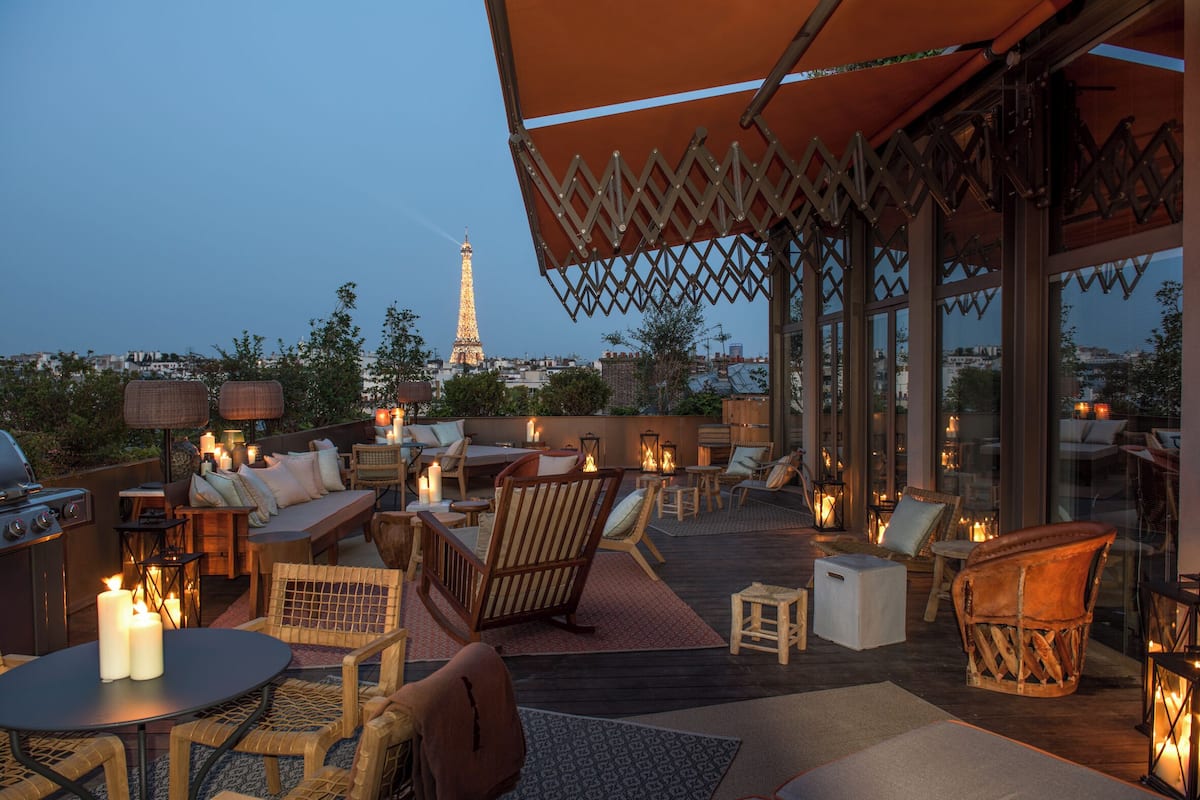 Un espacio al aire libre con mobiliario de mimbre, velas y vistas a la Torre Eiffel.