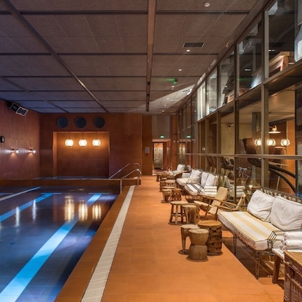 A spa area with a pool, lounge chairs, and a glass wall.