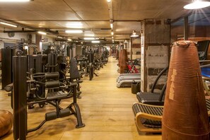 A gym with various exercise machines, a treadmill, and a punching bag.