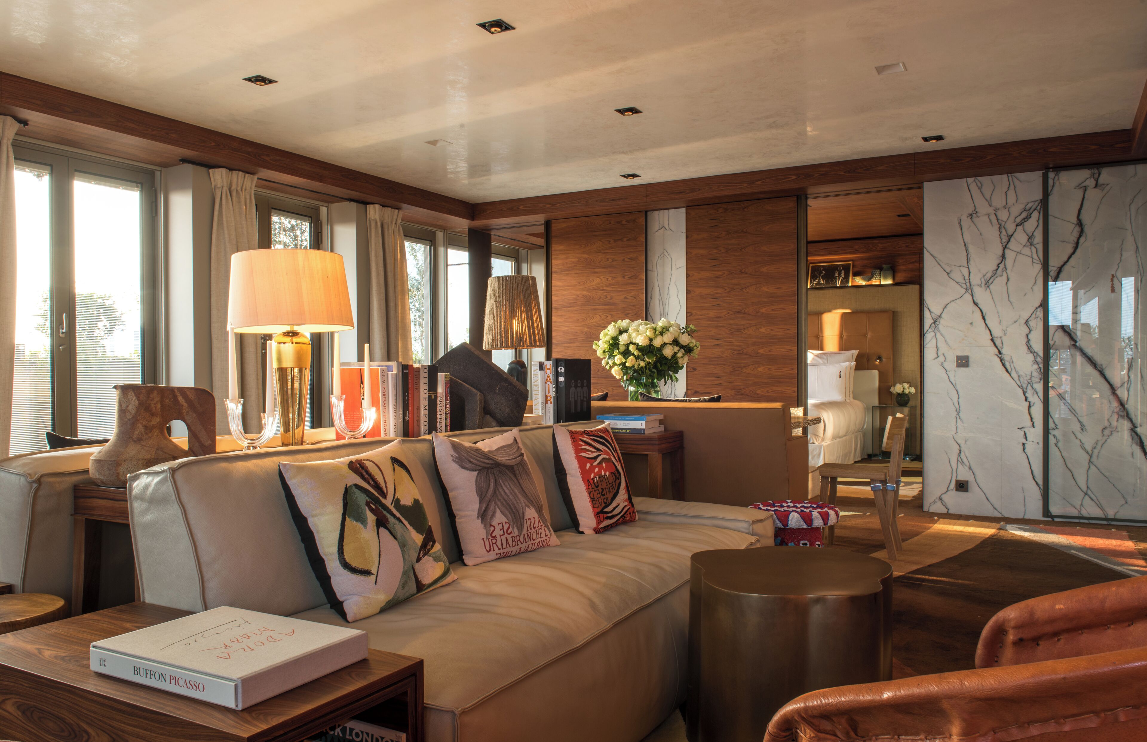 Un salon moderne avec un canapé, une table basse et une lampe. On trouve des livres et un vase sur la table basse.
