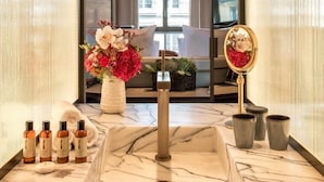 A bathroom with a marble sink, a mirror, and a vase of flowers. - Brach Paris - Evok Collection (Paris)