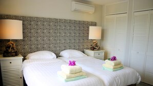 Une chambre d’hôtel avec un grand lit, deux tables de chevet, une tête de lit à motifs et une armoire.