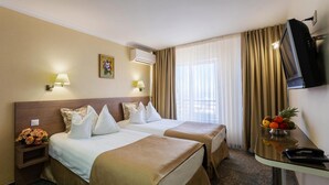A hotel room with two beds, a TV, a desk with a fruit bowl, and a lamp. - Hotel Stil (Cluj-Napoca)