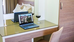 A laptop on a glass table with a wine glass and a picture frame. - Hotel Stil (Cluj-Napoca)