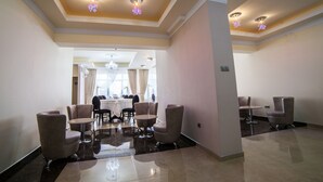 A spacious hotel lobby with a dining area, modern furniture, and decorative ceiling lights. - Hotel Stil (Cluj-Napoca)