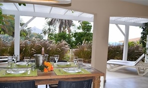 An outdoor dining area with a table set for four, surrounded by lush tropical plants.