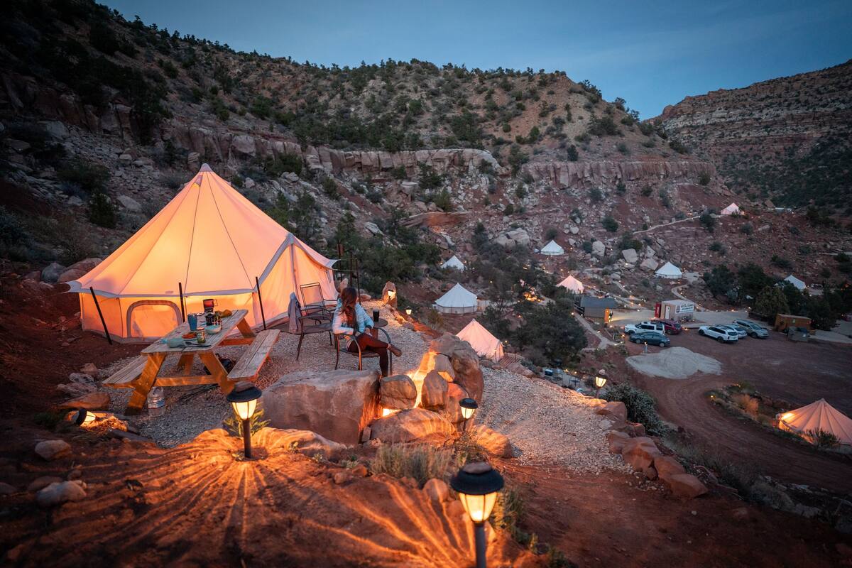 A campsite with tents, a picnic table, and a rocky landscape.