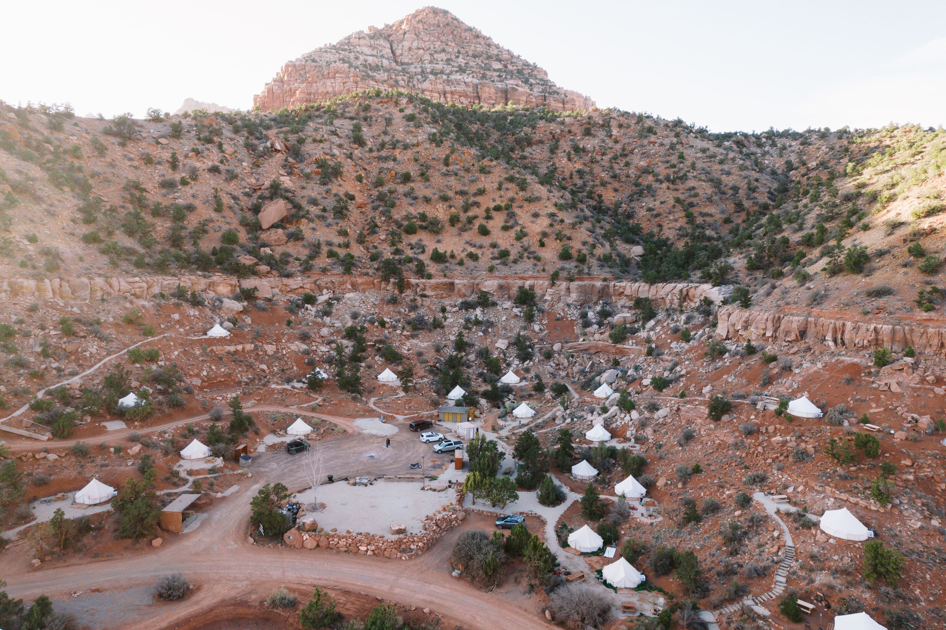 Vista aérea de un paisaje desértico con numerosas tiendas blancas dispersas en el terreno, rodeado de vegetación escasa y afloramientos rocosos.