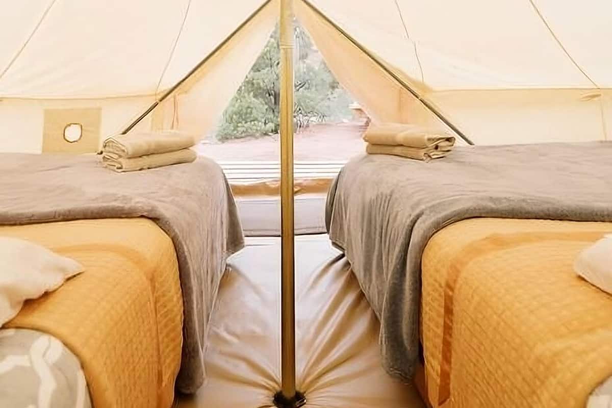 A tent with two beds, each with a pillow and a folded blanket.