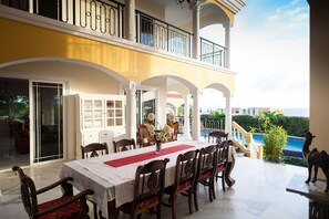 A dining area with a table set for six, surrounded by wooden chairs with red cushions, a white tablecloth, and a red runner. - Villa with Spectacular Sea View (Jan Thiel)