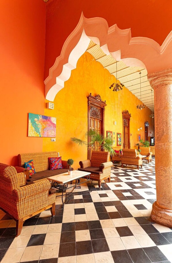 A lobby with a checkered floor, wicker furniture, and a large archway. - Viva Merida Hotel Boutique (Mérida)