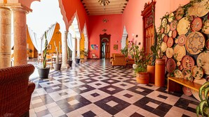 Eine Lobby mit Schachbrettmuster-Boden, Blumentöpfen, Korbmöbeln und einer Wand, die mit gewebten Körben geschmückt ist.