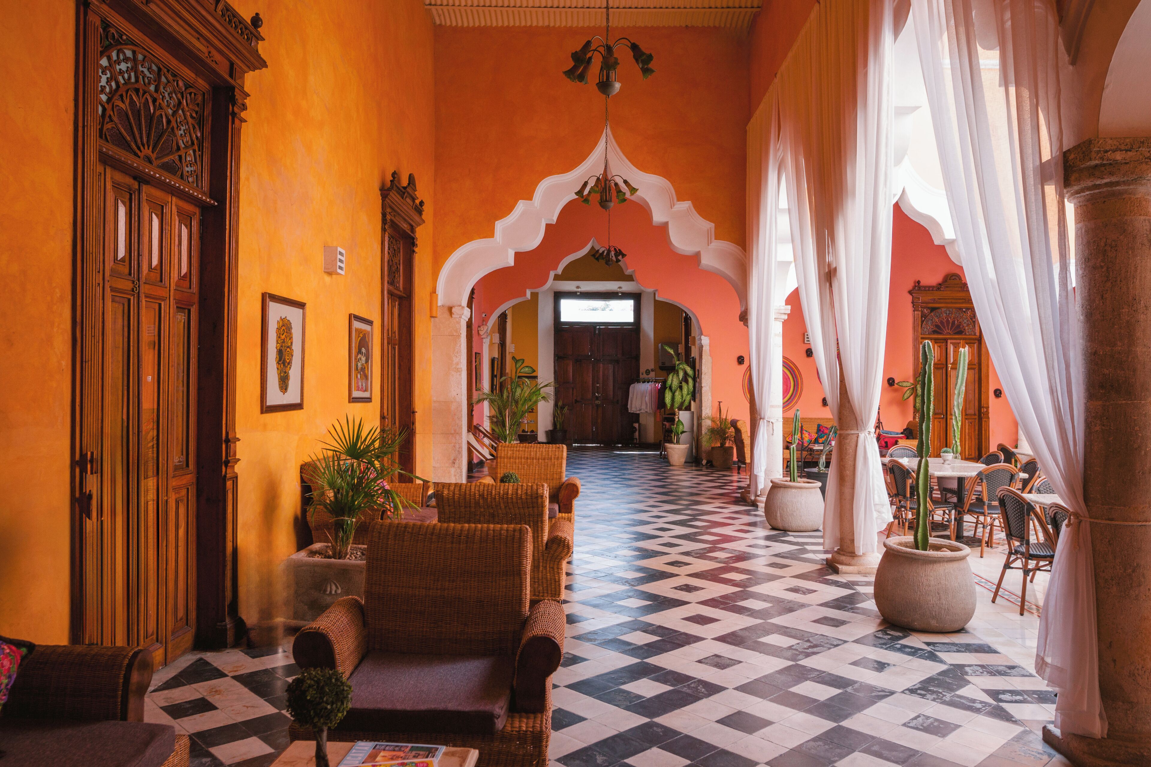 A hotel lobby with a checkered floor, wicker furniture, and a large wooden door.