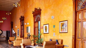 Eine Lobby mit Schachbrettmuster-Boden, Korbmöbeln und einer großen Holztür.