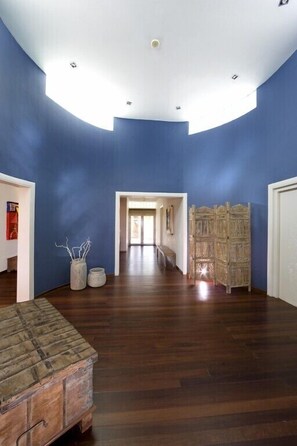 A spacious room with a high ceiling, wooden flooring, and a blue accent wall.
