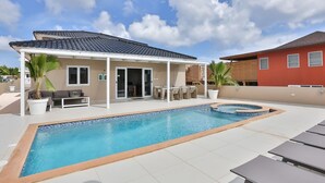 En swimmingpool med ett täckt uteområde, solstolar och en bubbelpool.