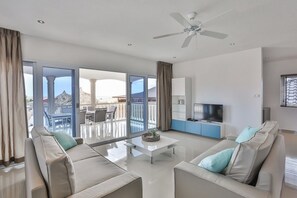 Ett modernt vardagsrum med en soffgrupp, ett soffbord, en tv och en takfläkt.