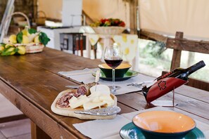Une table en bois avec un plateau de fromages, une bouteille de vin et un verre de vin rouge.